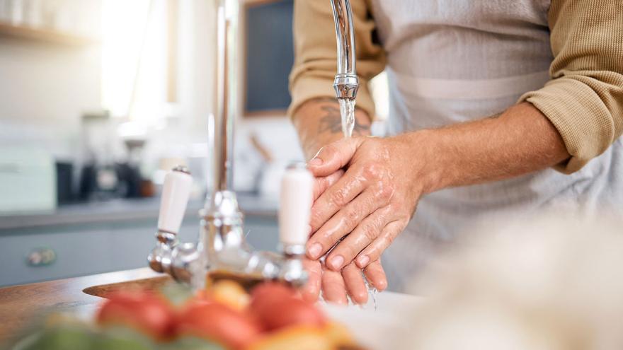 Ein Mann wäscht seine Hände am Spülbecken einer Küche