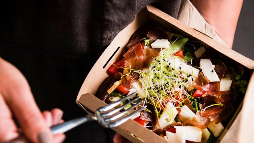 Jemand isst aus einer Pappbox seine vom Restaurant mitgenommenen Reste  