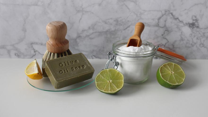 Holzbürsten, aufgeschnittene Limetten und weißes Pulver in Glasbehälter - plastikfreie Putzmittel