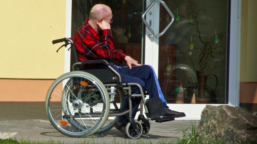 Ein Mann im Rollstuhl sitzt vor der Tür einer Betreuungseinrichtung