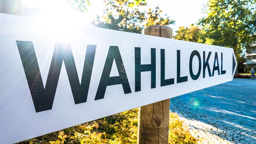 Ein Wegweiser mit der Beschriftung "Wahllokal" im Sonnenschein