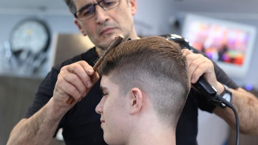 Ein Friseur schneidet einem jungen Mann die Haare 