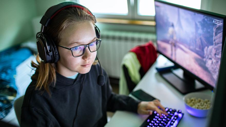 Ein Mädchen mit Kopfhören sitzt am PC beim Gaming