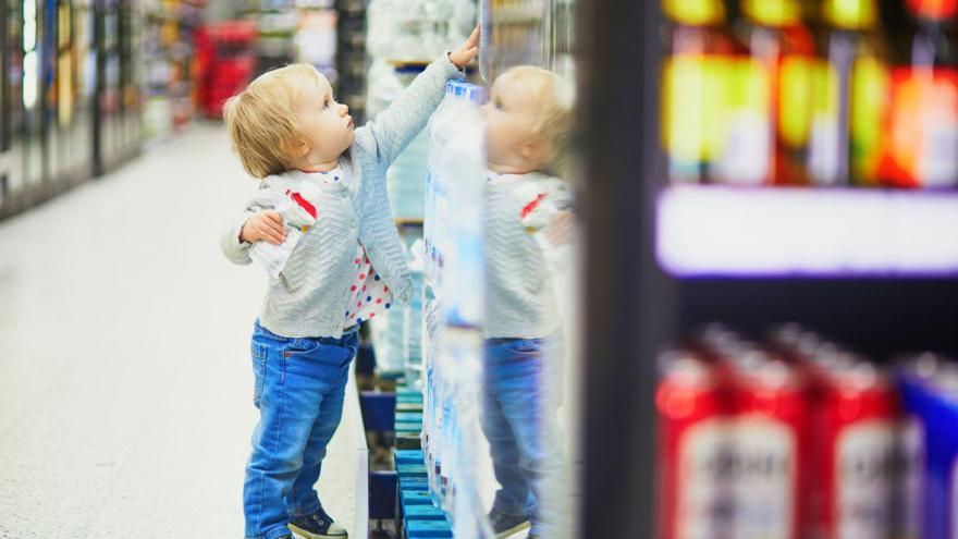 Ein Kind steht in einem Supermarkt und greift nach oben ins Regal 