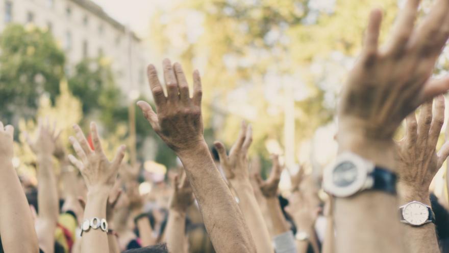 Menschen strecken bei Demonstration die Hände in die Luft