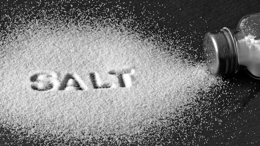 Auf dem Tisch ausgestreutes Salz, in das das Wort "salt" geschrieben ist