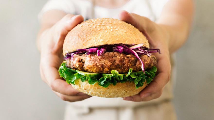 Hände halten einen Burger mit vegetarischem Patty