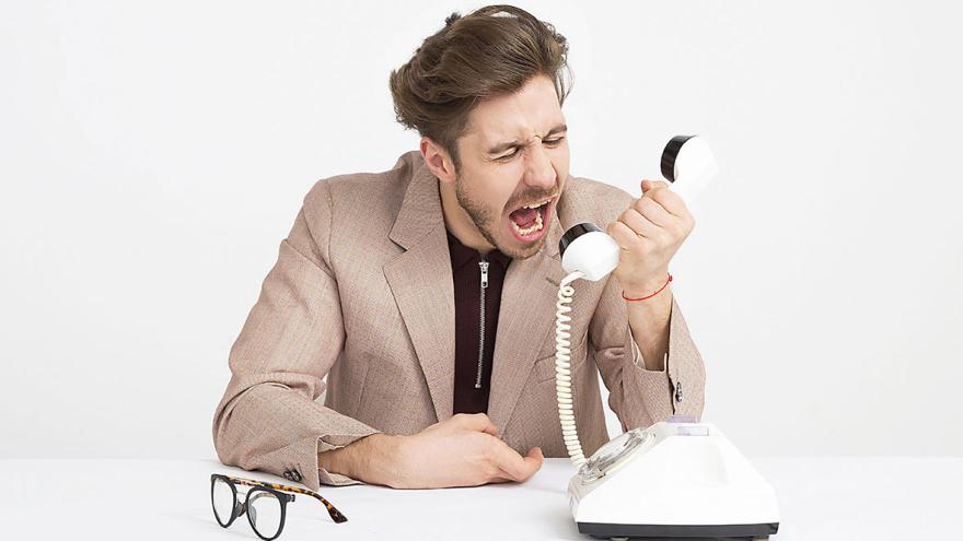 Ein junger Mann schreit verärgert in den Telefonhörer