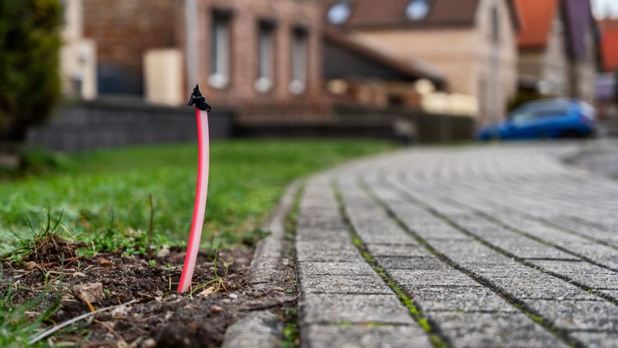 Ein Stück Glasfaserkabel ragt aus dem Boden in einem Wohngebiet