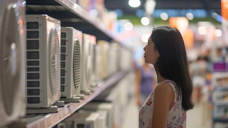 Eine Verbraucherin steht in einem Geschäft vor einem Regal mit Wärmepumpen