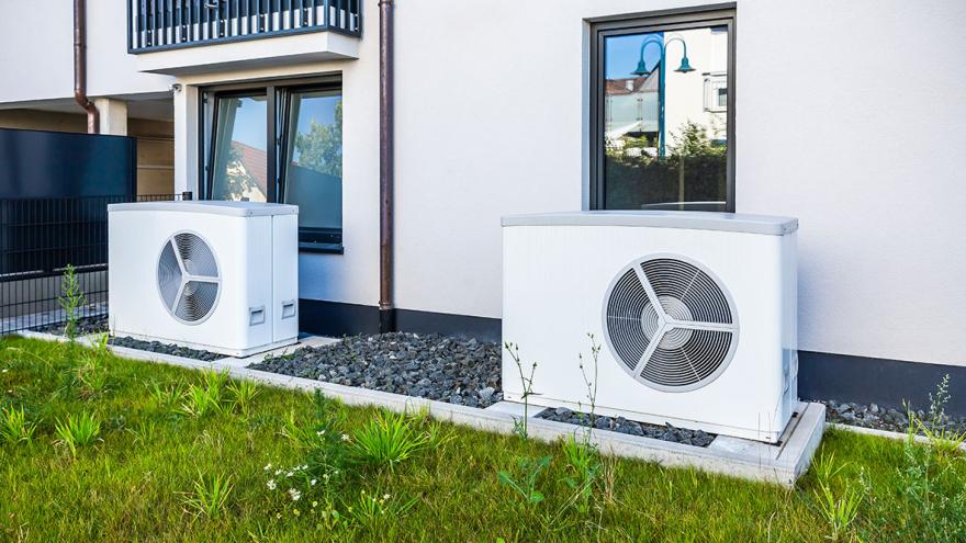 Zwei Wärmepumpen stehen vor der Hauswand eines Mahrfamilienhauses