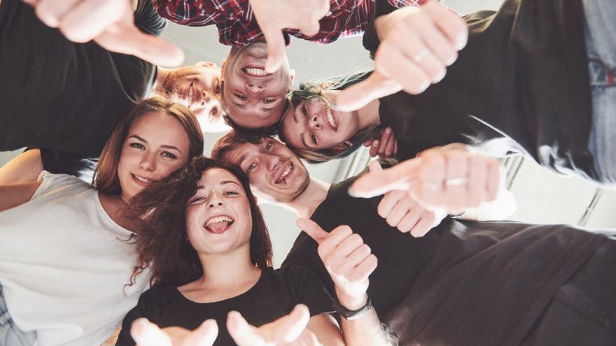 Eine gruppe Jugendliche bildet einen Kreis und sieht in die Mitte zum Foto 