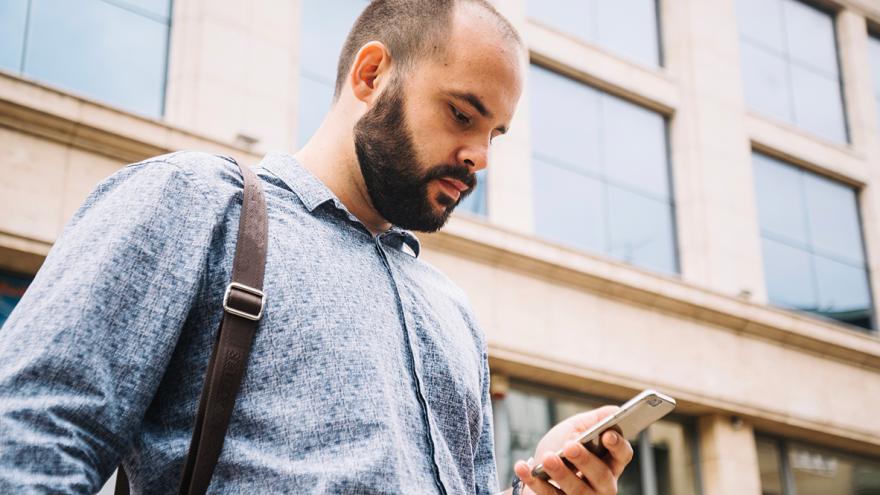 Ein Mann schaut irritiert auf das Display seines Smartphones