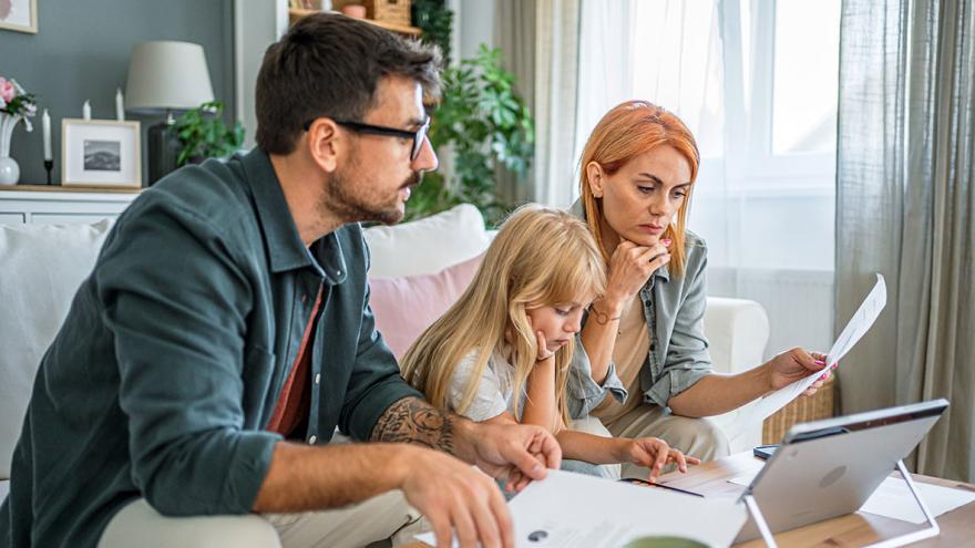 Eine Familie sitzt auf dem Sofa und studiert Unterlagen
