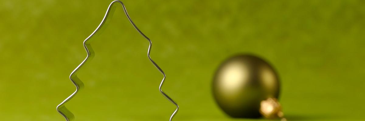 Weihnachtsbaum-Ausstecher und Weihnachtskugel vor grünem Hintergrund