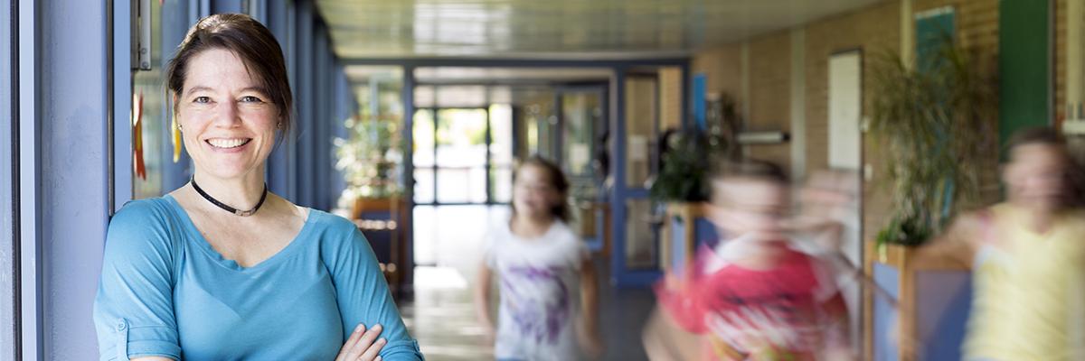 Lehrerin auf einem Schulflur, Kinder rennen vorbei