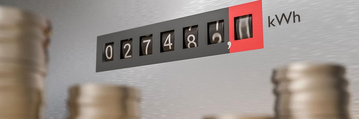 Ein Stromzähler, davor Stapel von Geldmünzen