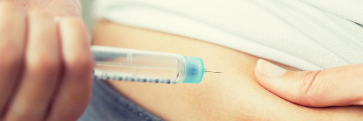 Jemand setzt sich eine Spritze an den Bauch