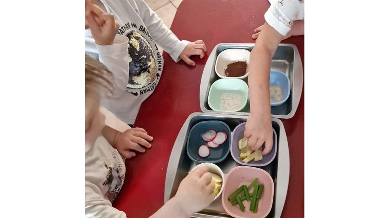Kinder erkunden verschieden Lebensmittel, die in Schälchen auf einem tisch stehen