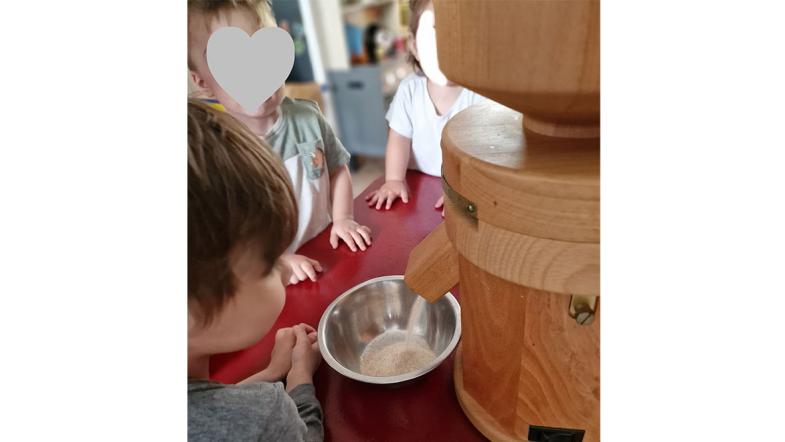 Kinder sehen beim Mahle der Getreidemühle zu 