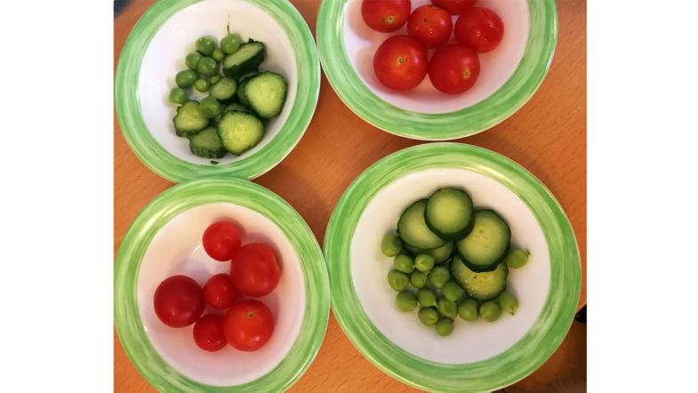 Teller mit Tomaten, Erbsen und Gurken aus dem Kita-Garten 