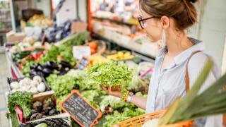 Junge Frau beim Einkauf an einem Gemüsestand 