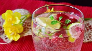 Ein Glas Wasser mit aromatisierenden Kräutern und Zitronenspalten 