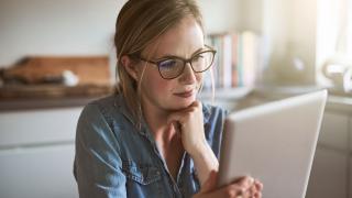Eine Frau betrachtet mit skeptischem Blick ihren Tablet-PC 