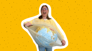 eine junge Frau zerreißt die Plastikhülle, in die ein Modell der Erde eingepackt ist