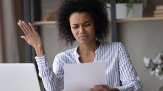 Eine Frau schaut verärgert auf einen Brief