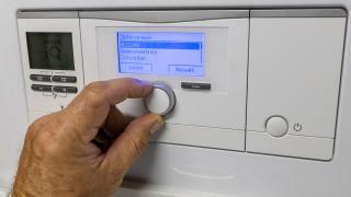 Jemand stellt die Temperatur an einer Heiztherme ein