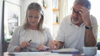 Ein Paar mittleren Alters blickt besorgt auf Unerlagen