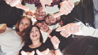 Eine gruppe Jugendliche bildet einen Kreis und sieht in die Mitte zum Foto 