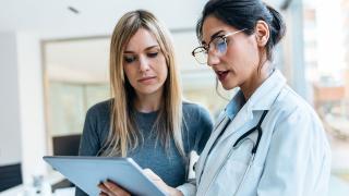Eine Ärztin erklärt einer Patientin einen Befund am Tablet-PC  