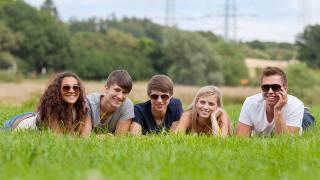Eine gruppe junger Erwachsener liegt auf einer Wiese