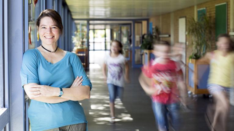 Lehrerin auf einem Schulflur, Kinder rennen vorbei